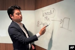 Yoshihito Hasegawa, who heads Tokyo-based TRK that runs a job-quitting service called Guardian, shows a diagram to explain what his service does at his office in Tokyo on June 21, 2023. (AP Photo/Yuri Kageyama)
