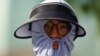 Seseorang mengenakan alat pelindung matahari di tengah gelombang panas yang menerpa Ibu Kota Beijing, China, 30 Juni 2023. (Foto: REUTERS/Tingshu Wang)