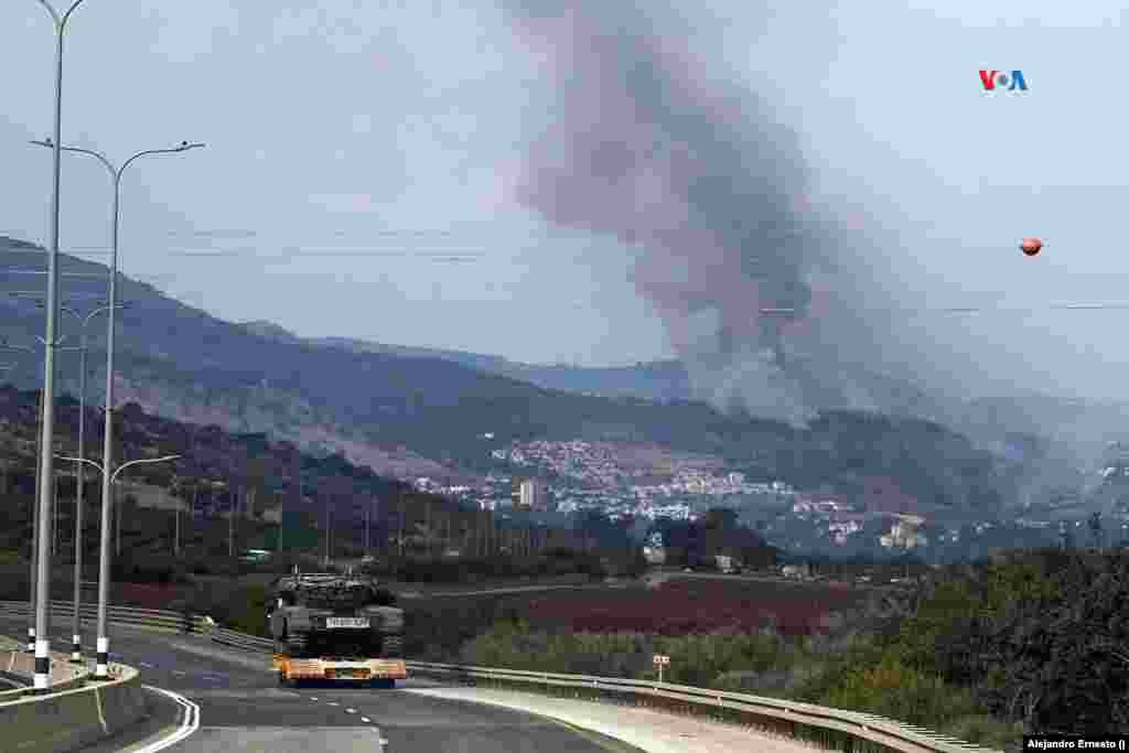 Un tanque israelí es transportado por una carretera, mientras se observa el humo del impacto de un proyectil lanzado desde el Líbano, el 31 de octubre de 2023.
