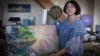 Oksana Kordina sostiene su pintura que creó para conmemorar a su esposo, un soldado que murió en una batalla con las tropas rusas, en un estudio de arte en Kiev, Ucrania, el sábado 3 de junio de 2023.