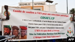 Des partisans de l'Alliance des États du Sahel (AES) brandissent leur bannière alors qu'ils célèbrent le départ du Mali, du Burkina Faso et du Niger de la Communauté économique des États de l'Afrique de l'Ouest (CEDEAO), à Niamey, le 28 janvier 2024. (Photo HAMA BOUREIMA / AFP)