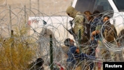 Seorang migran, yang masih anak-anak, tampak berlutut di depan Pasukan Penjaga Perbatasan AS di Texas, meminta untuk dibolehkan memasuki AS setelah melewati pagar berduri dari Ciudad Juarez, Meksiko, pada 30 Januari 2024. (Foto: Reuters/Jose Luiz Gonzalez)