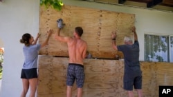 Residents cover the windows of their home in preparation for the arrival of Hurricane Beryl in Bridgetown, Barbados, June 30, 2024. 