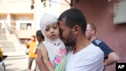Seorang pria Palestina di Khan Younis, Jalur Gaza, mengucapkan selamat tinggal kepada anaknya sebelum sang anak dibawa menuju Mesir untuk menjalani perawatan pada 27 Juni 2024. (Foto: AP/Abdel Kareem Hana)