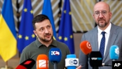 O Presidente ucraniano, Volodymyr Zelenskyy, à esquerda, e o Presidente do Conselho Europeu, Charles Michel, falam com os meios de comunicação social à chegada a uma cimeira da UE em Bruxelas, a 27 de junho de 2024.