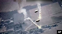 Foto dari tangkapan layar oleh Angkatan Udara AS tampak suar-suar yang dipasang di parasut melayang di udara. Suar-suar itu menurut AU AS dilepaskan oleh jet Rusia, SU-35, di atas wilayah udara Suriah, Rabu, 5 Juli 2023. (Foto: U.S. Air Force via AP)