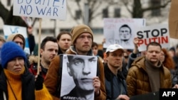 Seorang pria memegang foto Alexey Navalny pada aksi unjuk rasa di depan kedutaan Rusia di Berlin Minggu (18/2), menyusul kematian kritikus paling terkemuka Kremlin, Alexeiy Navalny, di penjara Arktik.