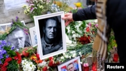 FILE - Seorang perempuan di Barcelona, Spanyol, menempatkan potret mendiang pemimpin oposisi Rusia Alexey Navalny, pada acara peringatan untuk menghormatinya, setelah penyerahan jenazah Navalny kepada ibunya di Salekhard, Arktik, 25 Februari 2024. (REUTERS/Nacho Doce)