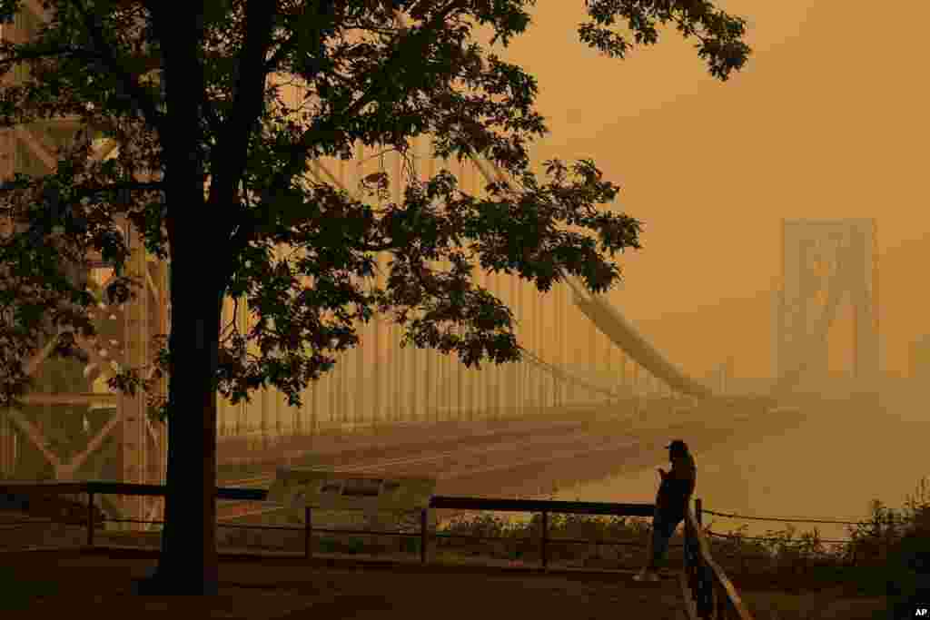A man talks on his phone as he looks through smoke from wildfires in Canada at the George Washington Bridge in Fort Lee, New Jersey, June 7, 2023.