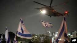 Moun flote drapo Izrayelyen nan moman yon elikopte kap transpote otaj Hamas lage nan Gaza rive nan sant medikal pou timoun Schneider la nan Petah tikva, Izrayel, Dimanch 26 Nov. 2023.