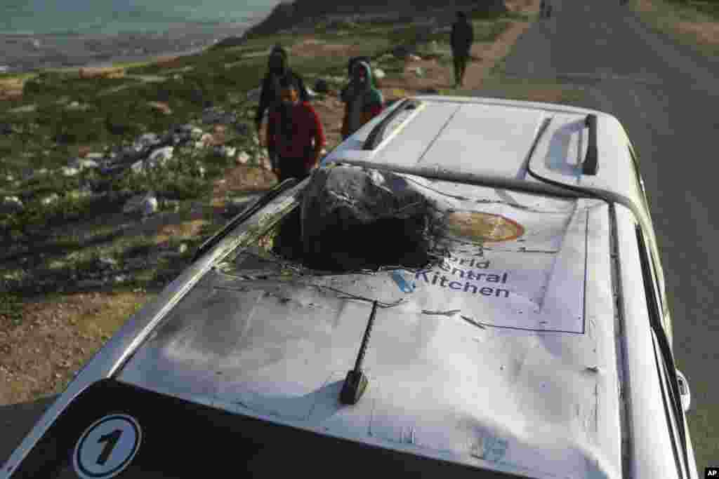 Palestinians inspect a vehicle with the logo of the World Central Kitchen wrecked by an Israeli airstrike in Deir al Balah, Gaza Strip, April 2, 2024. A series of airstrikes killed seven aid workers from the international charity, leading it to suspend delivery Tuesday of vital food aid to Gaza. 