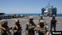 Sejumlah tentara AS berdiri di atas Dermaga Trident, dermaga sementara yang digunakan untuk mengirimkan bantuan masuk ke Jalur Gaza, di pesisir Gaza, pada 25 Juni 2024. (Foto: Reuters/Amir Cohen)