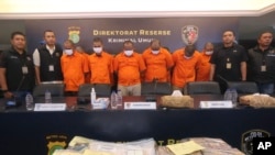 Indonesian police officers escort suspects and display the items of evidence during a press conference at Jakarta police headquarters in Jakarta, Indonesia, Thursday, July 20, 2023.