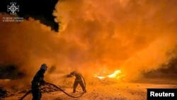 Petugas pemadam kebakaran memadamkan truk yang terbakar akibat serangan drone Rusia di kompleks pelabuhan di sungai Danube wilayah Odesa, Ukraina 26 September 2023. (Layanan pers Layanan Darurat Negara Ukraina di wilayah Odesa/Handout via REUTERS)