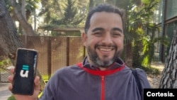 John Brimmer Giraldo sostiene su teléfono con la aplicación Íkualo, la cual le ofrece servicios bancarios siendo inmigrante en Europa.