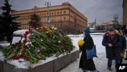 Para pelayat memberi penghormatan kepada Alexey Navalny, di tempat kamp pertama sistem penjara politik Gulag didirikan, dengan latar belakang gedung Dinas Keamanan Federal yang bersejarah, di Moskow, Rusia, 17 Februari 2024. (Foto: Alexander Zemlianichenko/AP Photo)