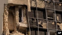 Seorang pria mengintip dari balik jendela gedung pemerintah yang rusak akibat serangan dronne Rusia di Kyiv, Ibu Kota Ukraine, 2 Agustus 2023. (Foto: Jae C. Hong/AP Photo(