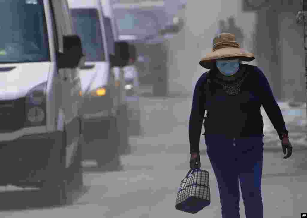 Una mujer camina por las calles cubiertas de ceniza del volcán Popocatépetl en Santiago Xalitzintla, México, el lunes 22 de mayo de 2023. No se han ordenado evacuaciones, pero las autoridades se preparan para ese escenario.