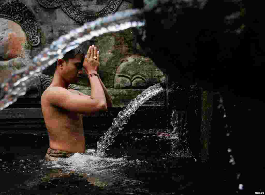 A Balinese Hindu prays before taking a bath during a cleansing ritual called Banyu Pinaruh, which is believed to purify their body and soul, at Tirta Empul temple's holy spring in Gianyar, Bali, Indonesia.
