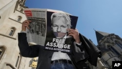 Демонстрант, протестирајќи против можната екстрадиција во САД на основачот на Викиликс Џулијан Асанж, чита весник пред Високиот суд во Лондон, 20 мај 2024 година