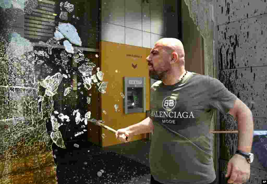 A protester smashes windows at Byblos Bank during a protest demanding the release of depositors' trapped savings, in Beirut, Lebanon, June 15, 2023.