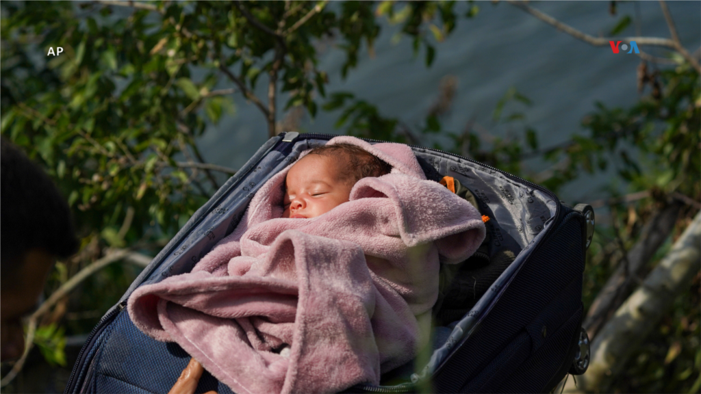 Migrantes cruzan el Río Bravo hacia Estados Unidos con un bebé en una maleta, visto desde Matamoros, México, el 10 de mayo de 2023. 