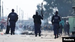 Des policiers sud-africains réagissent lors de la grève en cours des opérateurs de taxi contre les autorités chargées de la circulation au Cap, en Afrique du Sud, le 7 août 2023.