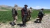 FILE - Armed Taliban security personnel walk along a wheat field in Argo district, Badakhshan province, on May 6, 2024. 