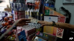 Un vendedor entrega cambio en moneda estadounidense a un cliente en Caracas, Venezuela. Foto de archivo. (Foto AP/Ariana Cubillos)