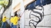 Reclusos del penal La Esperanza, escoltados por guardias, borran un grafiti vinculado a la pandilla Mara Salvatrucha durante un operativo que busca recuperar barrios controlados por pandillas en San Martín, El Salvador, el 22 de marzo de 2023.