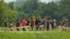 Migrantes caminan en fila después de acercarse a un funcionario cerca del Río Grande tras cruzar la frontera entre Texas y México, el 11 de mayo de 2023, en Brownsville, Texas.