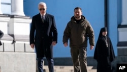 Presiden AS Joe Biden, kiri, berjalan bersama Presiden Ukraina Volodymyr Zelenskyy di Katedral Kubah Emas St. Michael dalam kunjungan mendadak, di Kyiv, Ukraina, Senin, 20 Februari 2023. (Foto: AP)