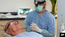 FILE - In this photo made June 26, 2009, Costa Rican Dr. Luis Obando, right, prepares to perform a root canal on Bill Jones, of Dallas, Texas at Meza Dental Care in San Jose, Costa Rica. (AP File photo)