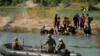 Penjaga mendorong para migran yang menunggu di gundukan pasir di tengah sungai Rio Grande untuk berbalik ketika mereka mencoba menyeberangi sungai tersebut dari Meksiko ke AS, Sabtu, 23 September 2023. (AP/Eric Gay)
