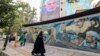 La gente pasa junto a una valla publicitaria que muestra un retrato del recién nombrado líder de Hamás, Yahya Sinwar (arriba), junto a la Plaza Palestina en Teherán, el 12 de agosto de 2024.