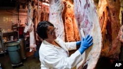 FILE - Stacey Richard memeriksa salah satu sisi daging sapi yang digantung di fasilitas Pengepakan Daging Wright di Fombell, Pa, pada Kamis, 16 Juni 2022. (AP/Keith Srakocic)