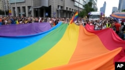 Para peserta pawai membawa bendera pelangi dalam pawai hak-hak LGBTQ tahunan di Warsawa, Polandia, 17 Juni 2023. (Foto: Czarek Sokolowski/AP Photo)