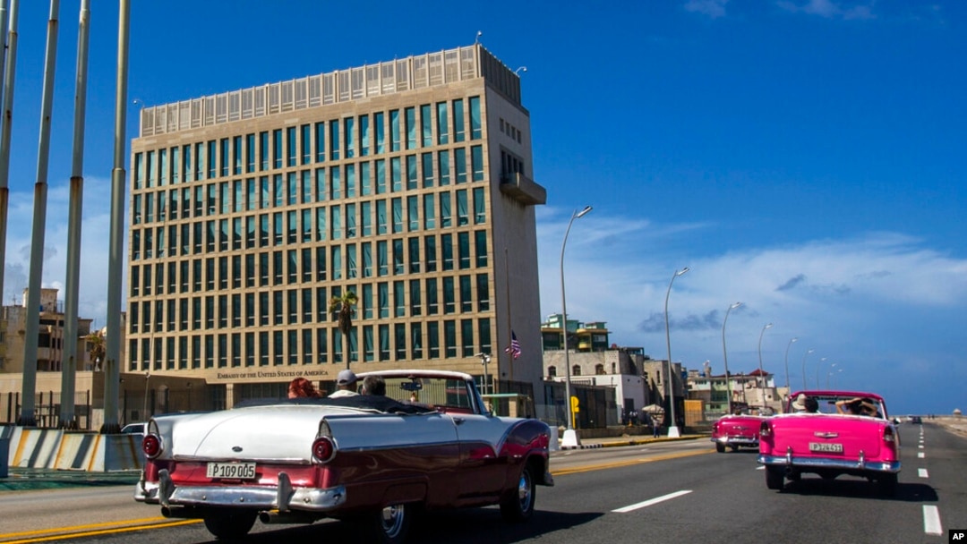 ARCHIVO - Turistas en autos clásicos pasan frente a la Embajada de EEUU en La Habana, Cuba, el 3 de octubre de 2017. 