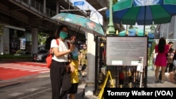 Warga Thailand membawa payung dan kipas angin portabel untuk melawan suhu udara yang panas menyengat di Bangkok (23/4). 