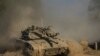 An Israeli soldier moves on the top of a tank near the Israeli-Gaza border, as seen from southern Israel, July 14, 2024. 