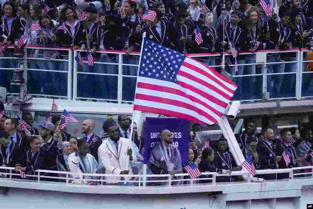 El barco que transporta al equipo de Estados Unidos, con Lebron James portando la bandera, avanza por el río Sena.