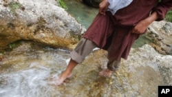 Seseorang penduduk berjalan di air mancur, yang pernah digunakan oleh penduduk setempat sebagai air minum, di pegunungan Alborz dekat desa Chalandar, sebelah utara Teheran, Iran, 8 Agustus 2002. (Foto: Kamran Jebreili/AP Photo)