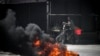 Warga Palestina melihat dari balik ban yang terbakar saat serangan Israel di kota Jenin di Tepi Barat yang diduduki, 21 Mei 2024.