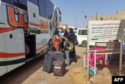 People wait with their luggage at a bus stop in southern Khartoum on May 8, 2023, as fighting continues between Sudan's army and the paramilitary forces.