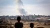 Dua anak laki-laki tampak memperhatikan asap yang mengepul dari sebuah araea di Rafah di saat pasukan Israel menyerang wilayah tersebut, pada 13 Mei 2024. (Foto: AFP)