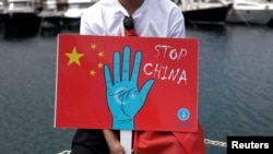 Seorang pria etnis Uighur memegang plakat ikut serta dalam protes terhadap China untuk menandai peringatan 14 tahun kerusuhan Urumqi di Istanbul, Turki, 5 Juli 2023. (Foto: Reuters)