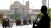 A police officer is silhouetted as he stands guard while paramilitary forces patrol as a security measure, following the visit of the Iranian President Ebrahim Raisi, in Karachi, April 23, 2024. 