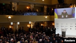 Ukrainian President Volodymyr Zelenskyy appears on the screen during the Munich Security Conference, in Munich, Germany, Feb. 17, 2023.