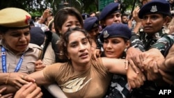 Pegulat India Vinesh Phogat (tengah) ditahan oleh polisi saat protes terhadap Brij Bhushan Singh, ketua federasi gulat, di New Delhi pada 28 Mei 2023. (Foto: AFP)