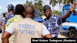 ARCHIVES - Un policier fait signe à un journaliste lors d'un sit-in près de la présidence, pour protester contre une nouvelle loi sur les médias à Lomé, au Togo, le 14 mars 2013.